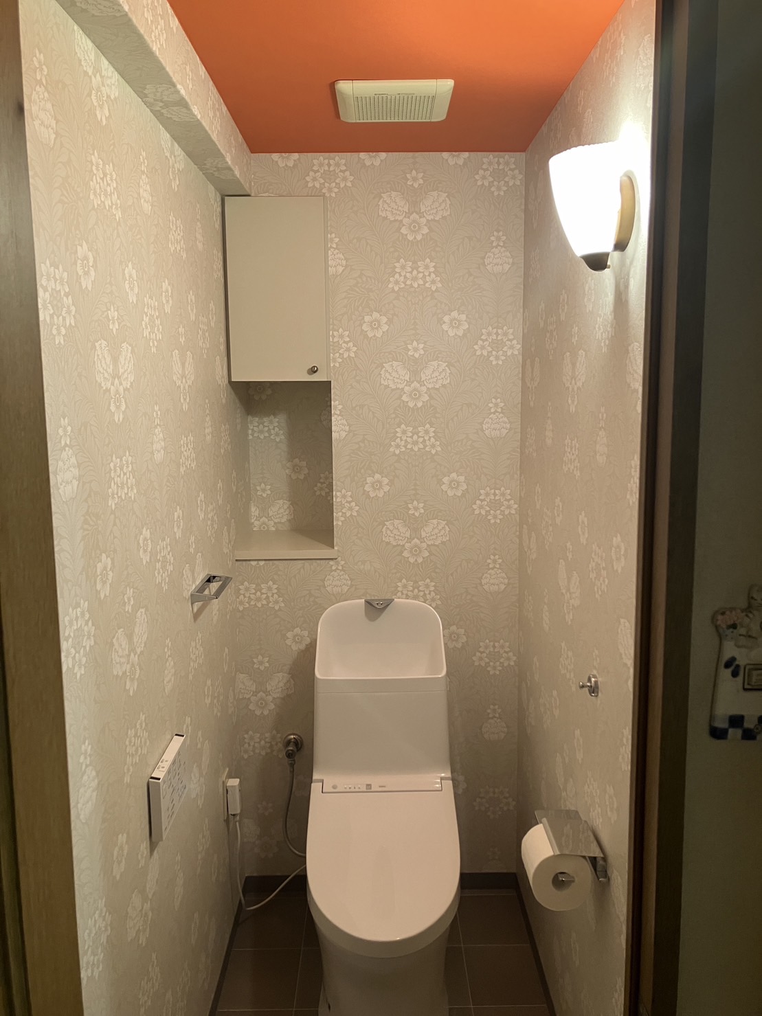 1dayリフォーム！メタリックで統一した小物×オレンジ系のアクセントクロスが映えるレストルーム